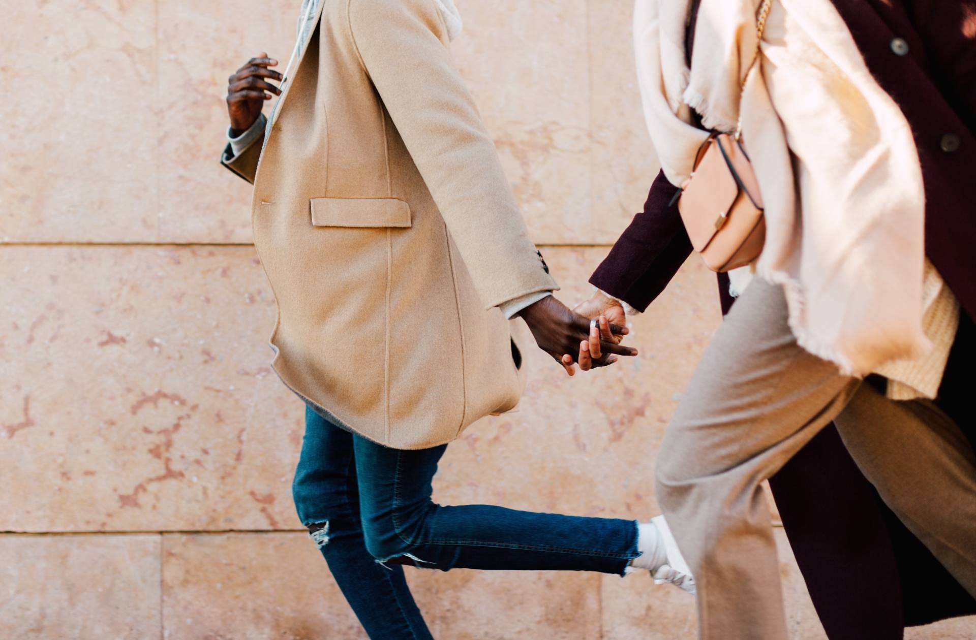 Two people bundled up in coats and walking hand in hand.